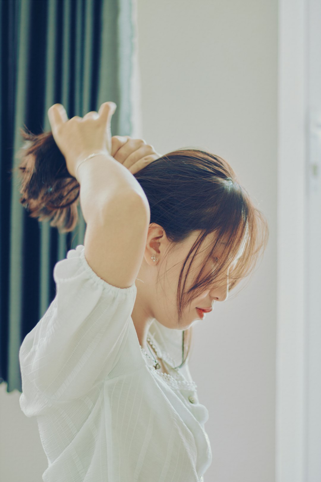 woman in white shirt holding her hair