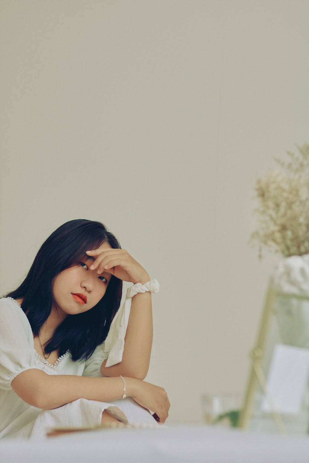 woman in white shirt leaning on white wall