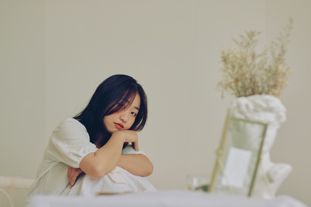 woman in white long sleeve shirt sitting on white bed