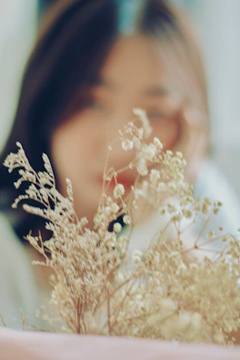 Soft-focus image of the model in a serene garden setting with blooming flowers.