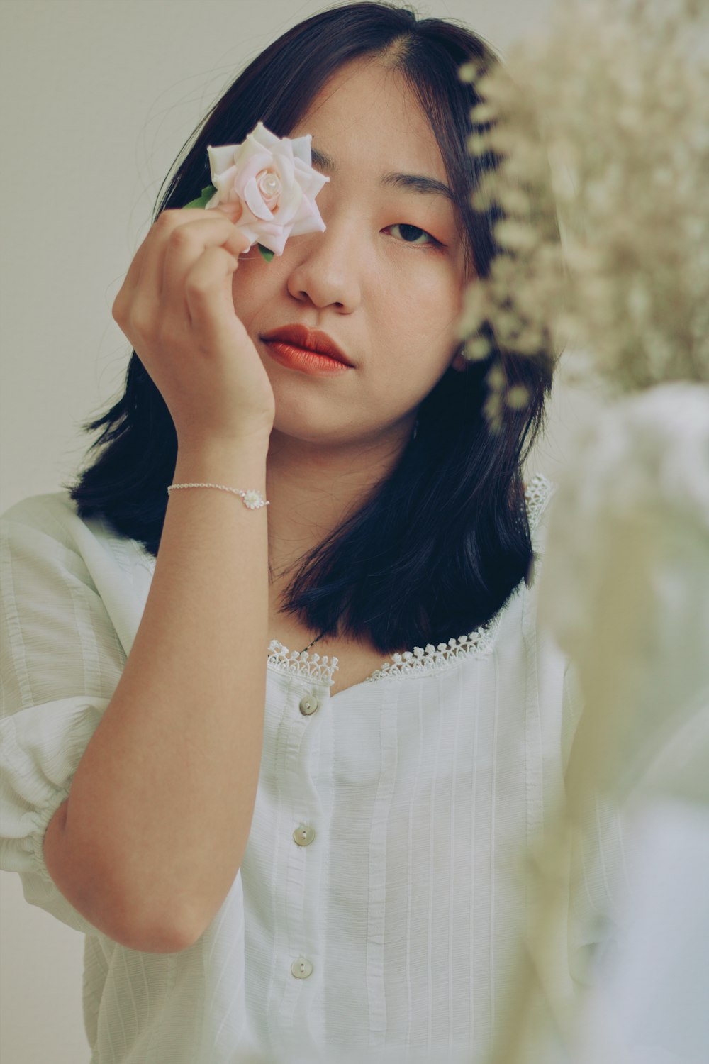 woman in white button up shirt holding white flower