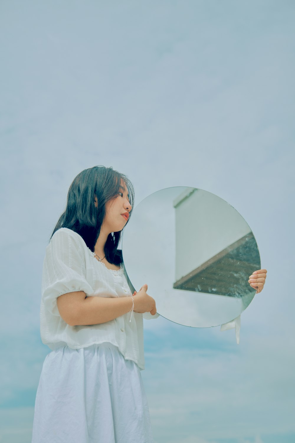 girl in white dress shirt holding heart shaped mirror
