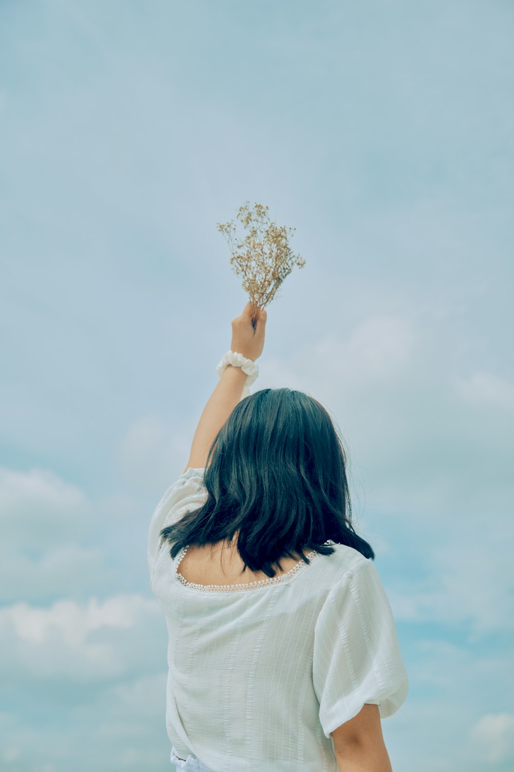 woman in white shirt holding white flower