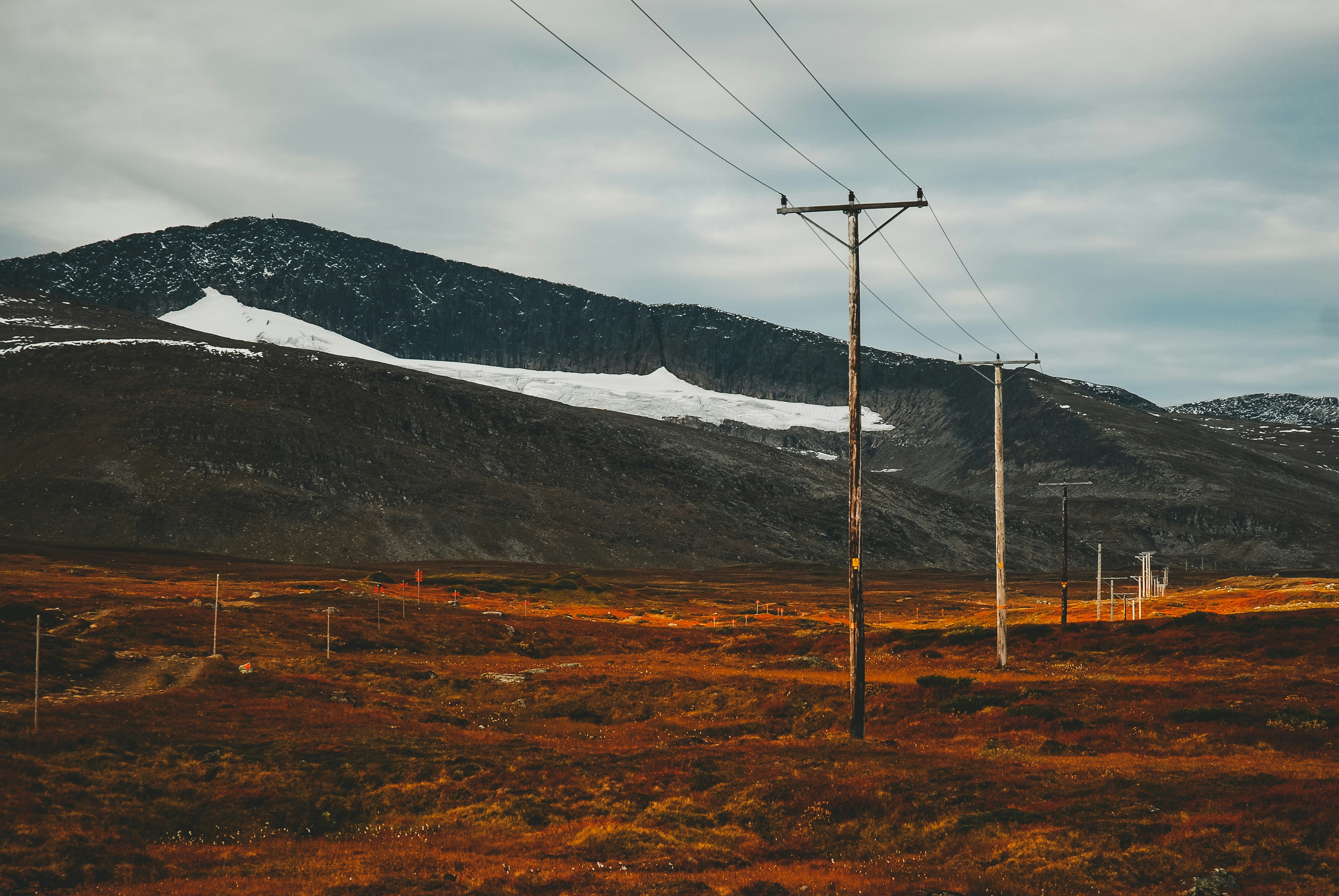 brown grass field near mountain under white sky during daytime