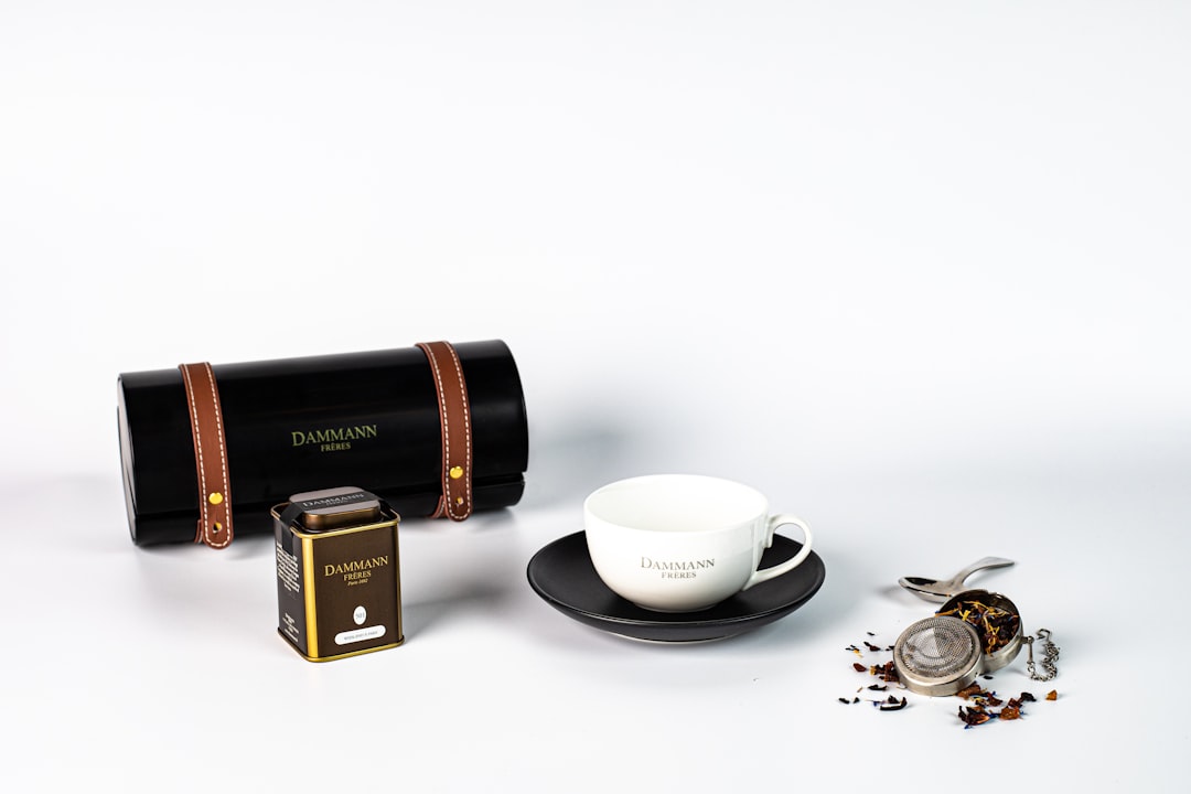 white ceramic teacup on saucer beside gold and black box mod