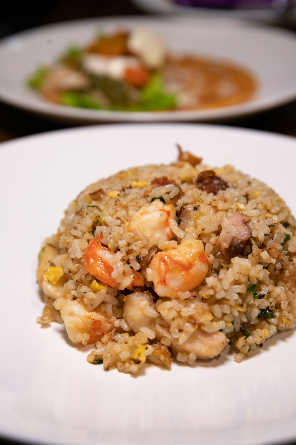 Arroz cocido con guisantes y rodajas de zanahoria en un plato de cerámica blanca