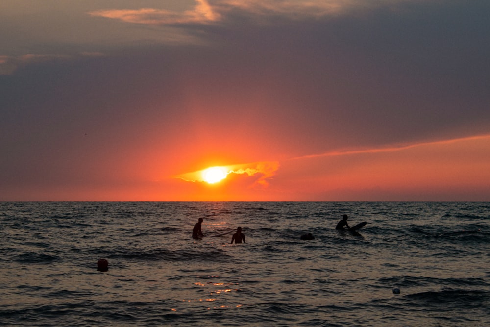 personnes à la plage pendant le coucher du soleil