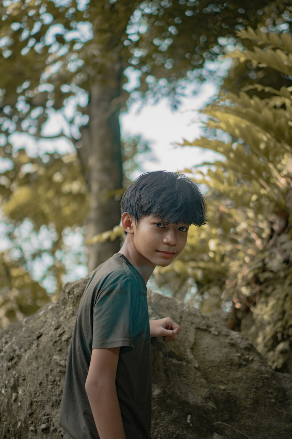 boy in grey crew neck t-shirt standing near tree during daytime