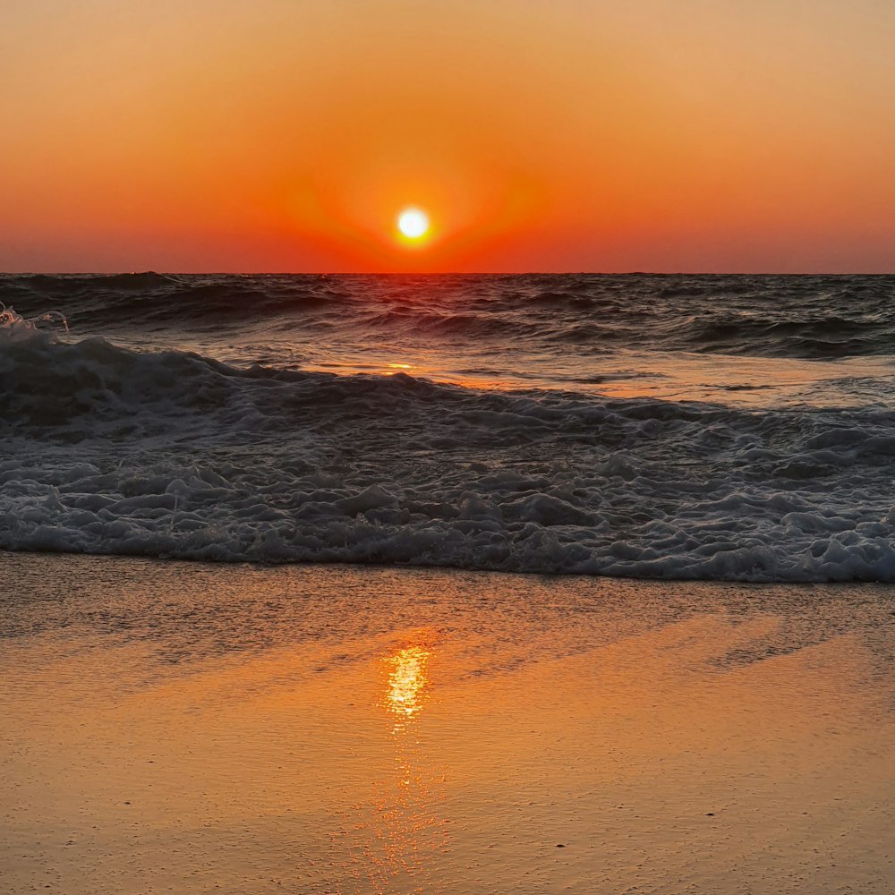 sea waves crashing on shore during sunset