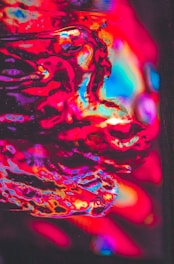 Close-up of vibrant psychedelic nail art with swirling orange and purple lava lamp colors and textured background.