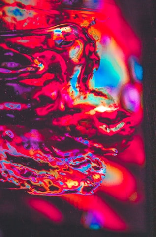 Close-up of vibrant psychedelic nail art with swirling orange and purple lava lamp colors and textured background.