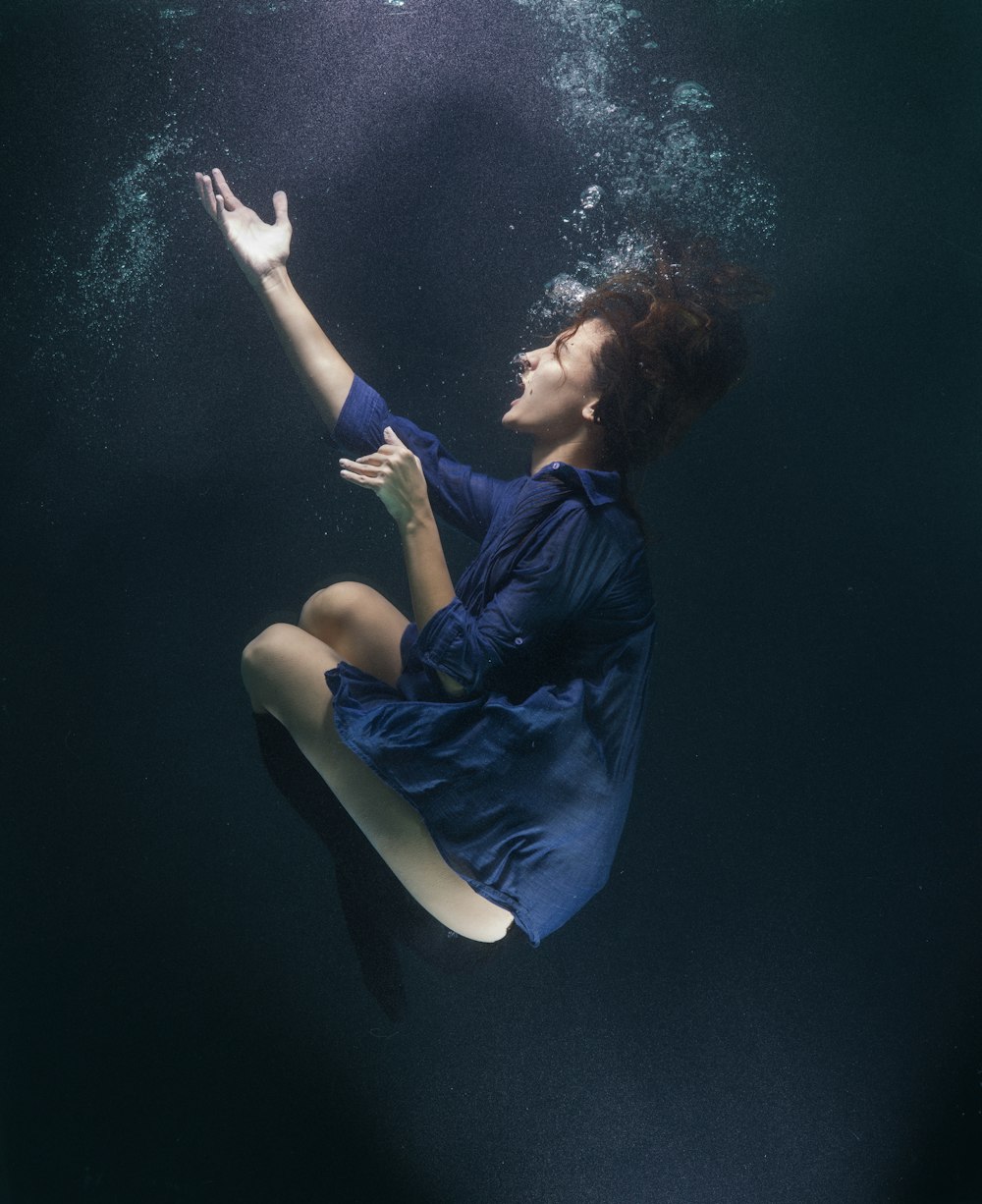 Mujer con camisa azul y pantalones blancos acostada sobre agua azul