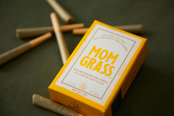An array of colorful pre-rolled joints neatly arranged on a hemp leaf background.