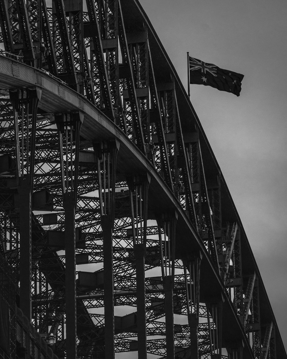 grayscale photo of flag of us a on top of bridge