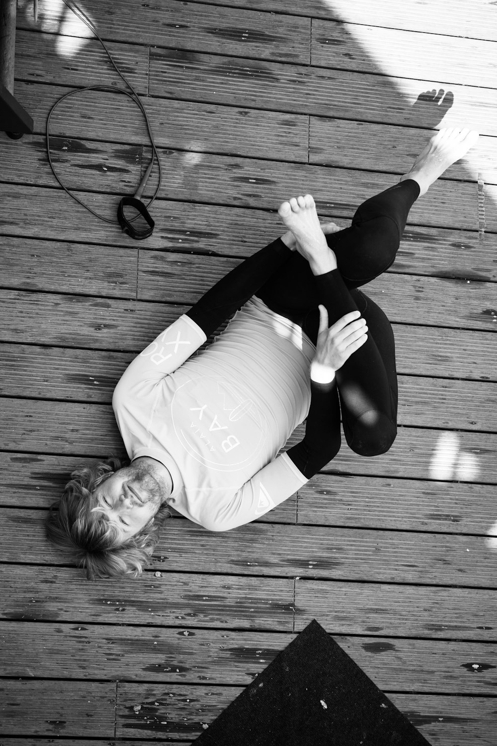 woman in white long sleeve shirt and black pants sitting on wooden floor