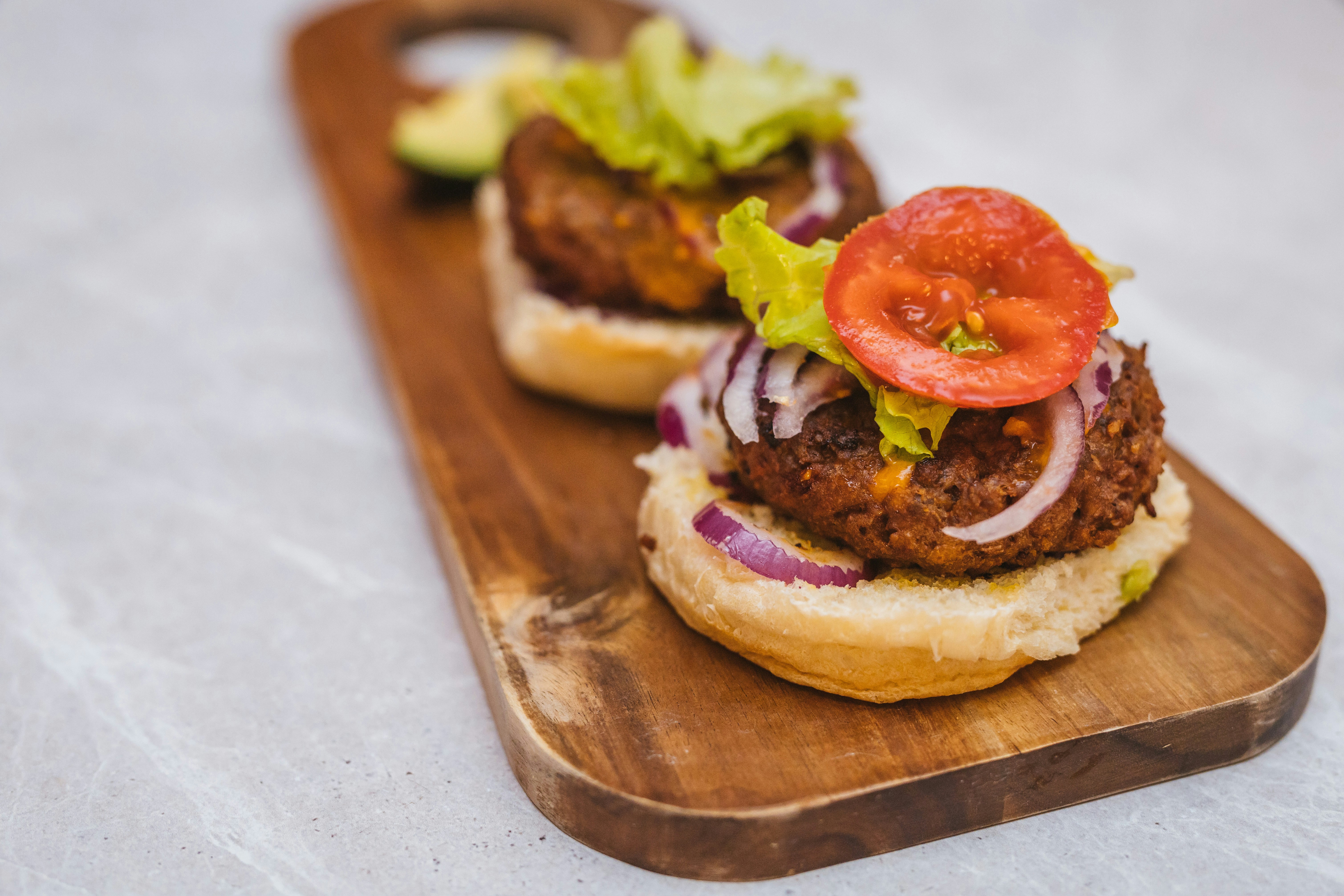 burger with tomato and lettuce on brown wooden chopping board
