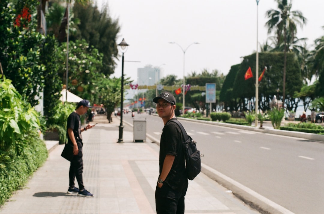 man in black t-shirt and black pants walking on sidewalk during daytime