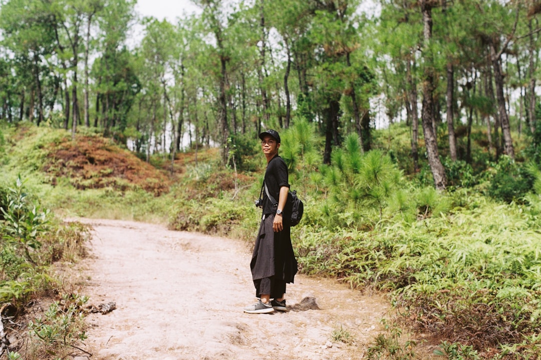 man in black robe standing on dirt road during daytime