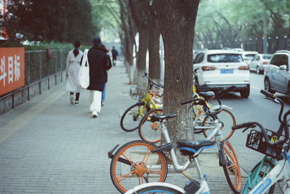 people walking on sidewalk near parked bicycle during daytime