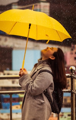 woman in gray jacket holding yellow umbrella