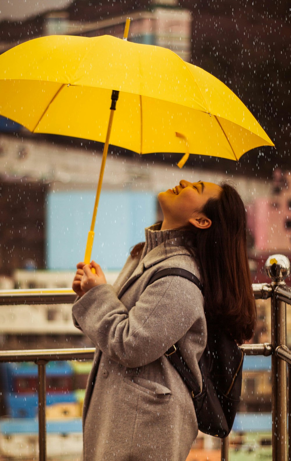 黄色い傘を持つ灰色のジャケットを着た女性