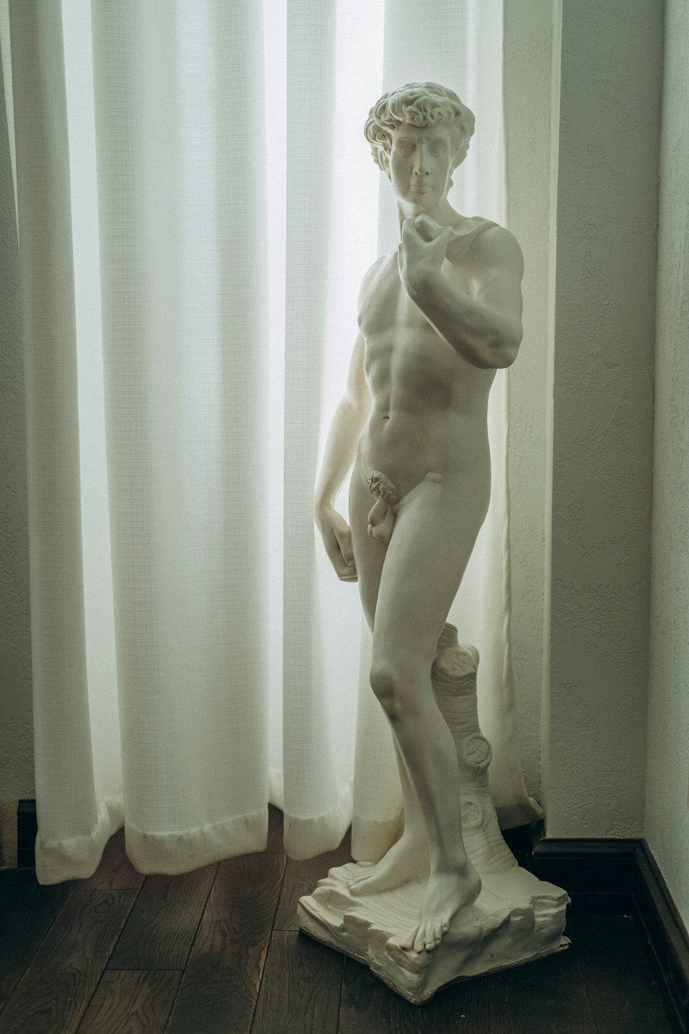 white ceramic statue near white window curtain