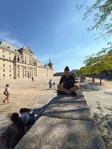 A digital nomad working on a laptop outdoors with a scenic Spanish city background.