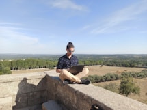 man with a laptop sitting on gray concrete bench during daytime
