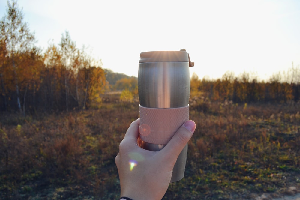 person holding stainless steel cup