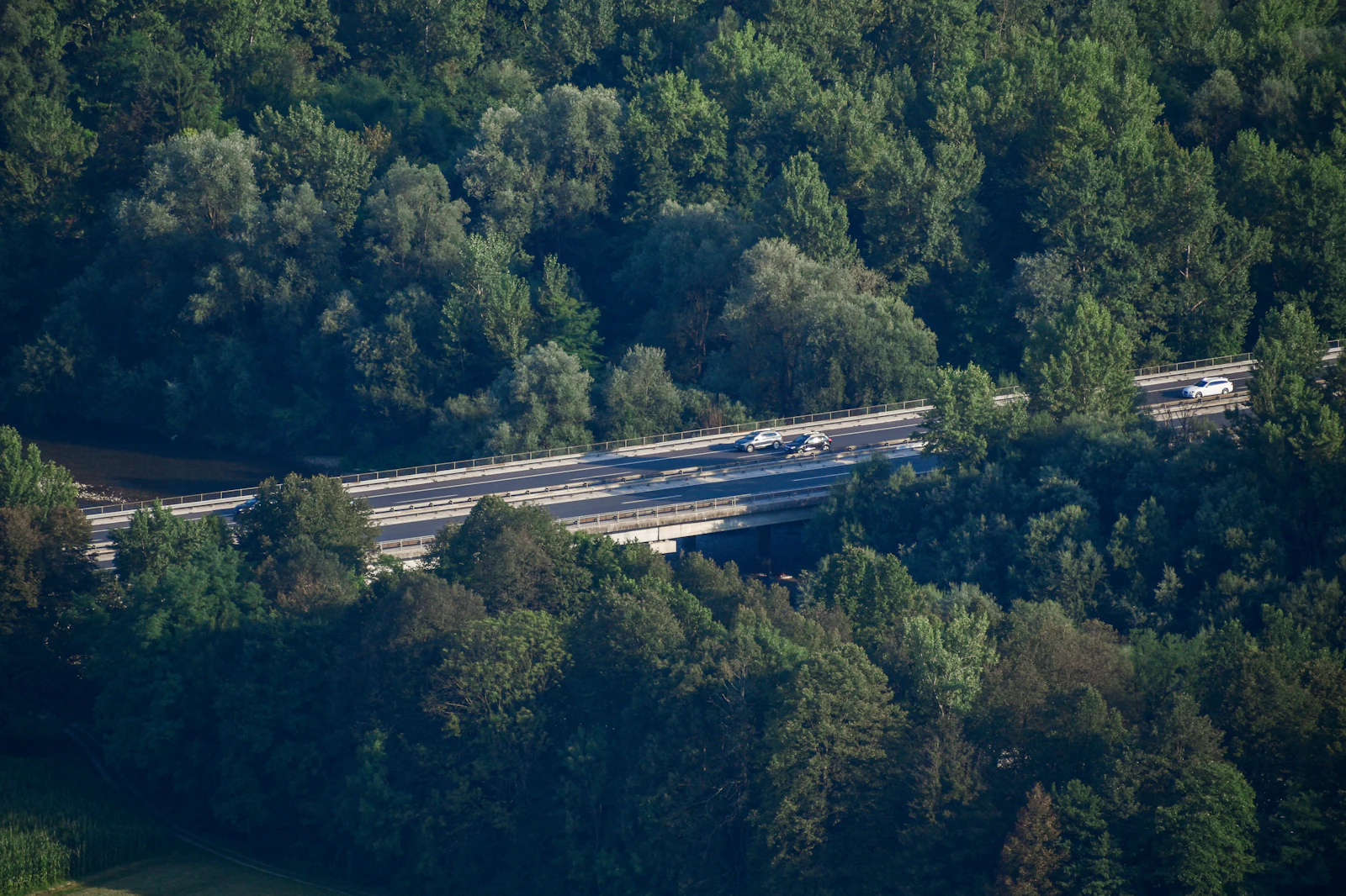 Slovenian motorway crosses a green valley beneath forested hills