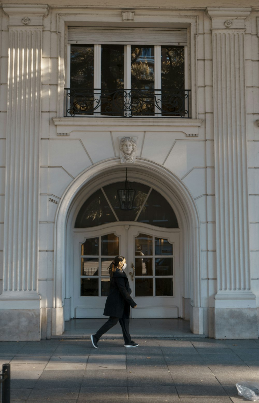 woman in black coat standing in front of white concrete building