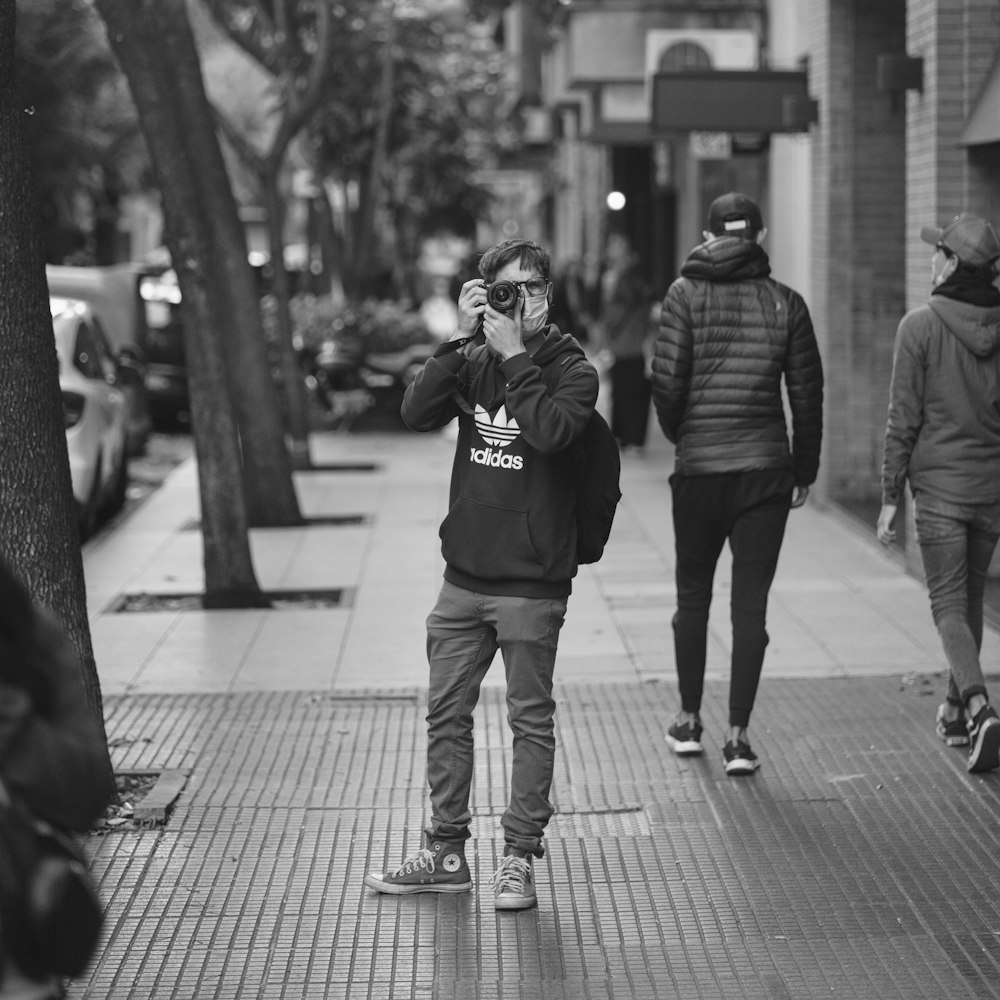 man in black jacket and white pants standing on sidewalk