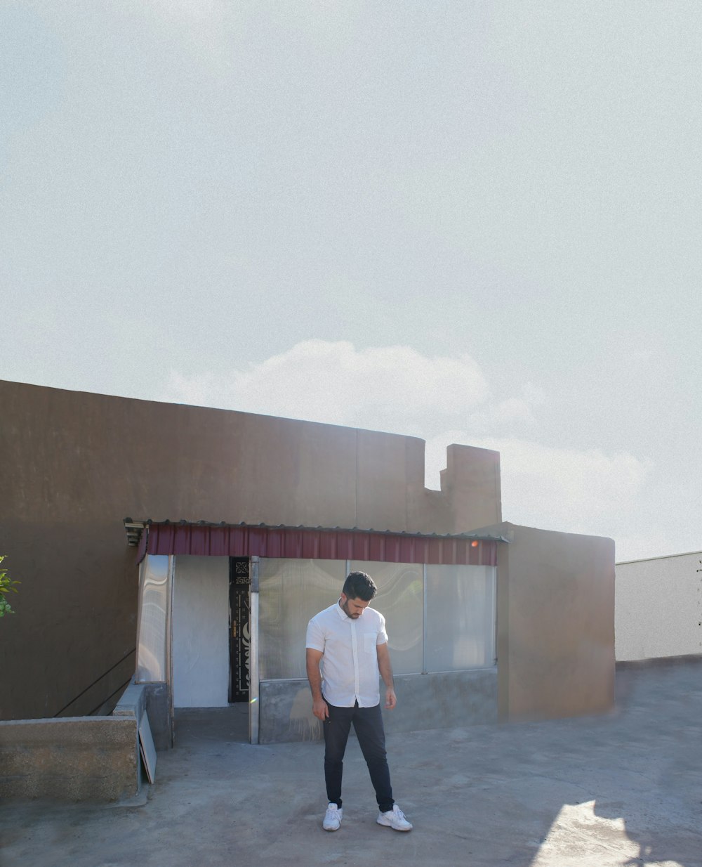 uomo in camicia bianca e pantaloni neri in piedi sul pavimento di cemento grigio