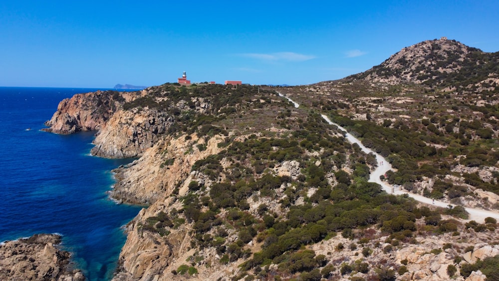 green and brown mountain beside blue sea under blue sky during daytime