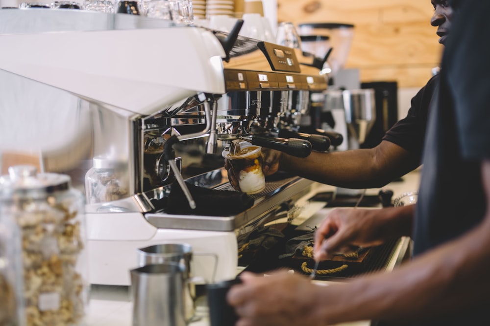 person in black shirt holding silver and black espresso machine