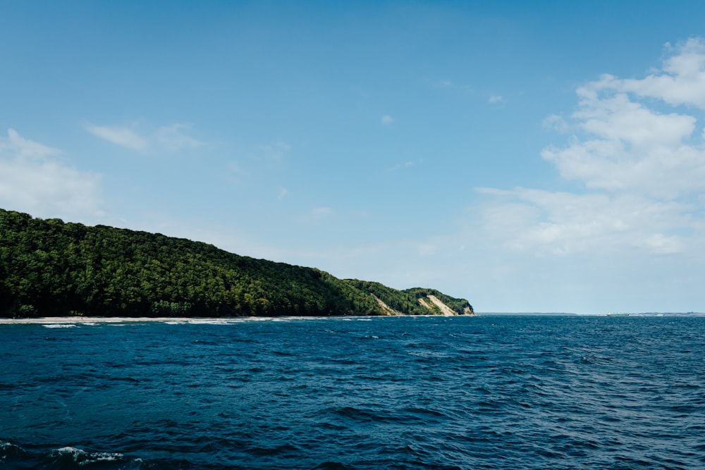 green mountain beside blue sea under blue sky during daytime