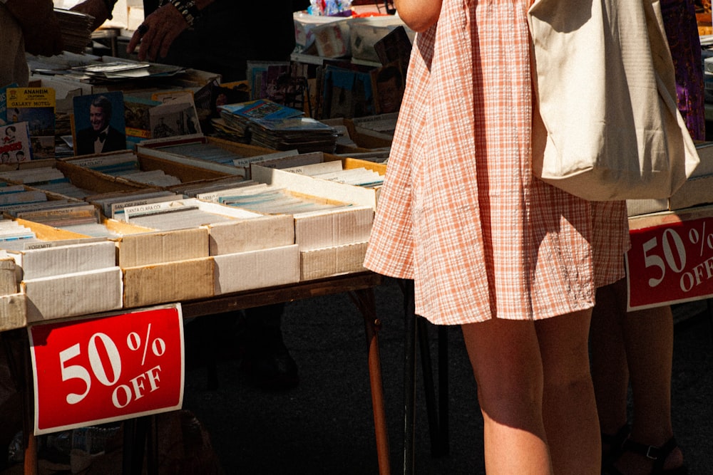 woman in white and red plaid dress standing beside brown wooden table