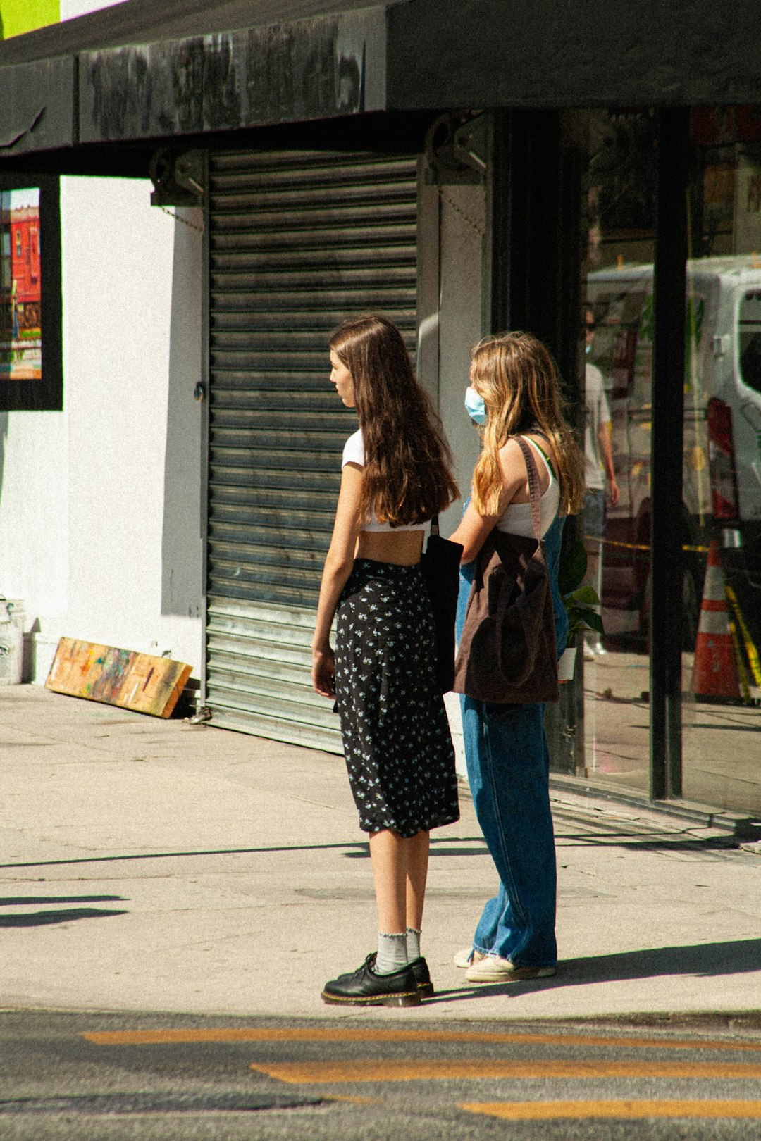 woman in black tank top and blue denim jeans standing beside woman in black shirt