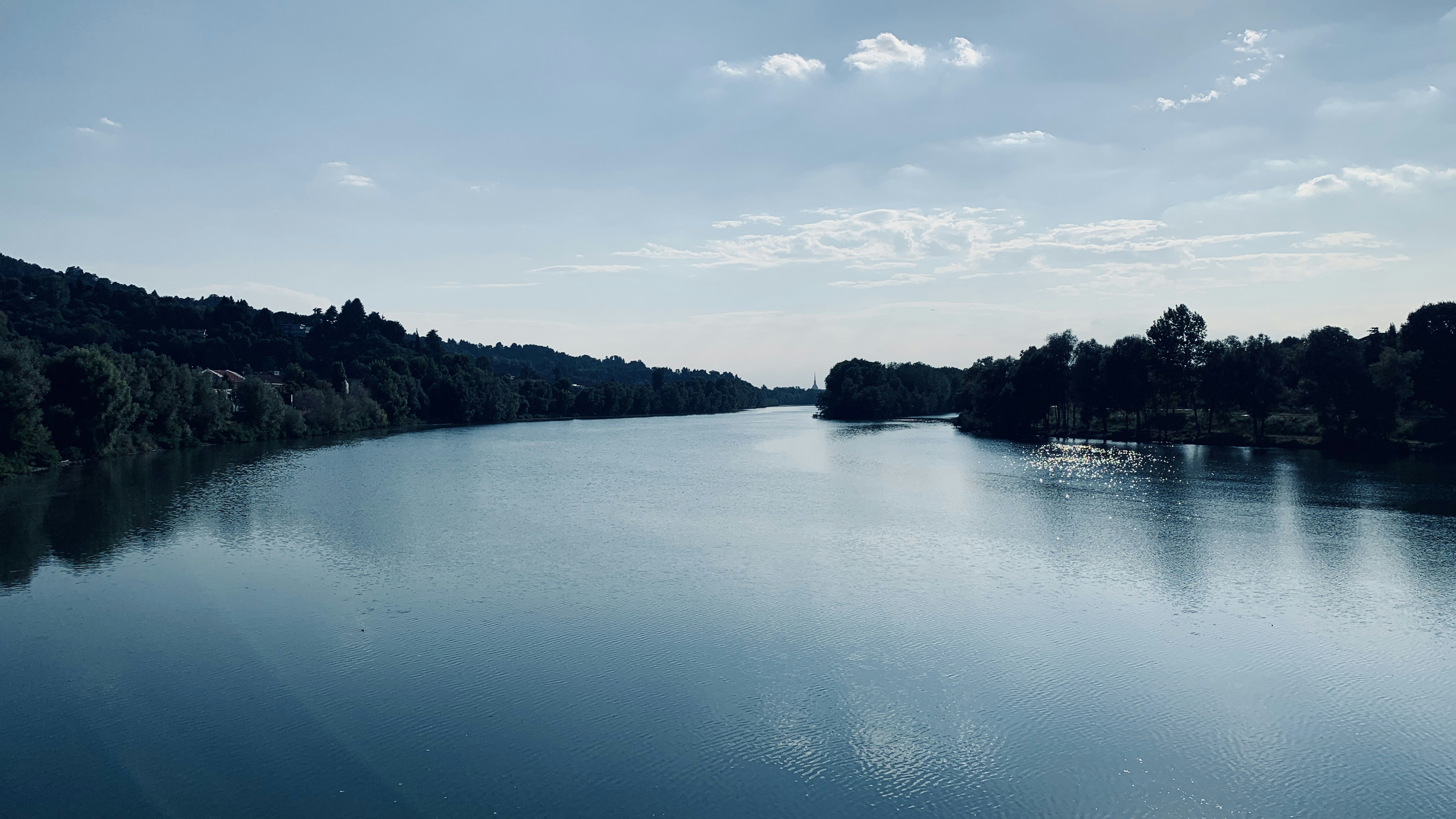 body of water near trees under white clouds during daytime