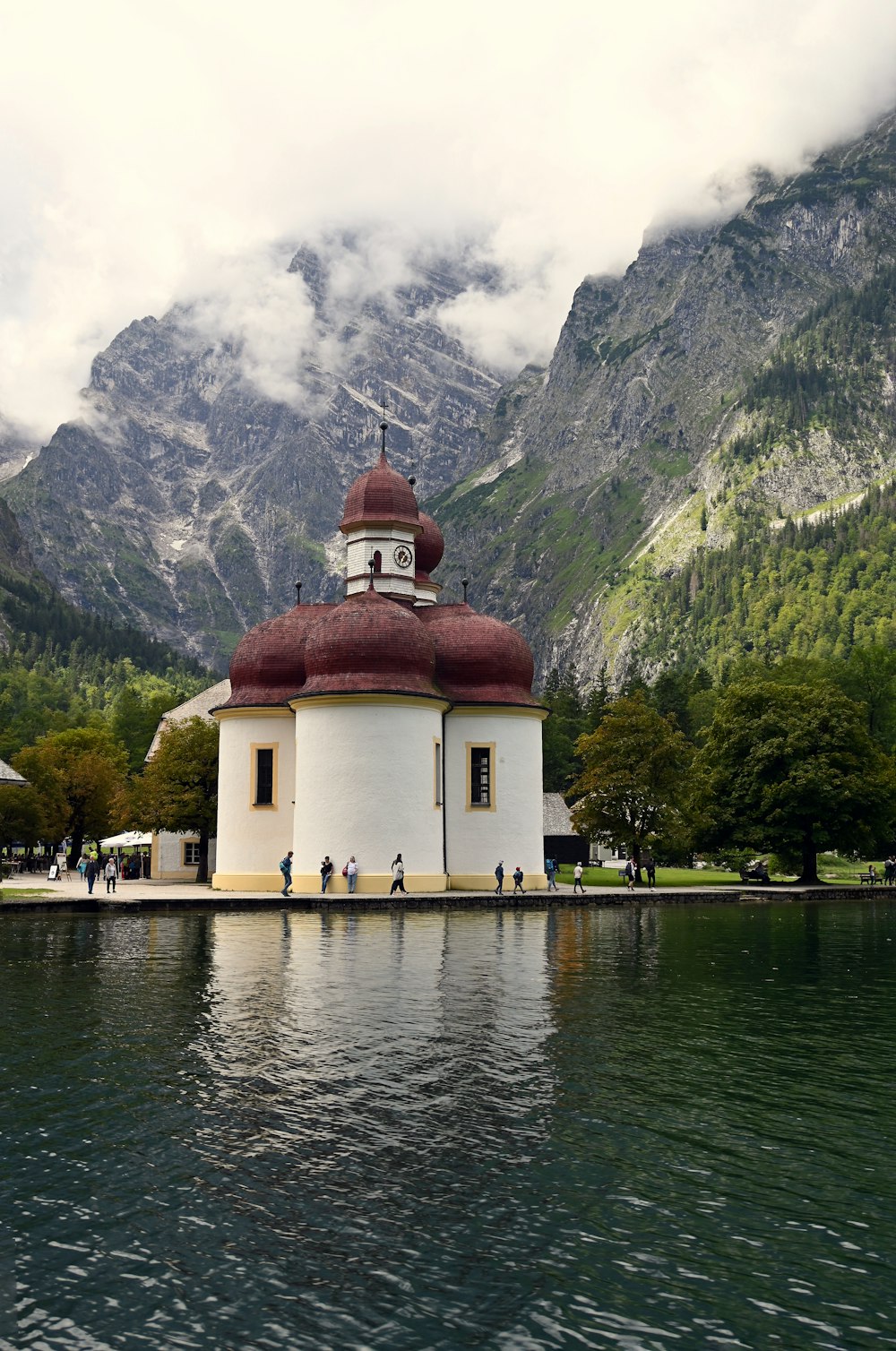 white and brown concrete building near body of water and mountain during daytime