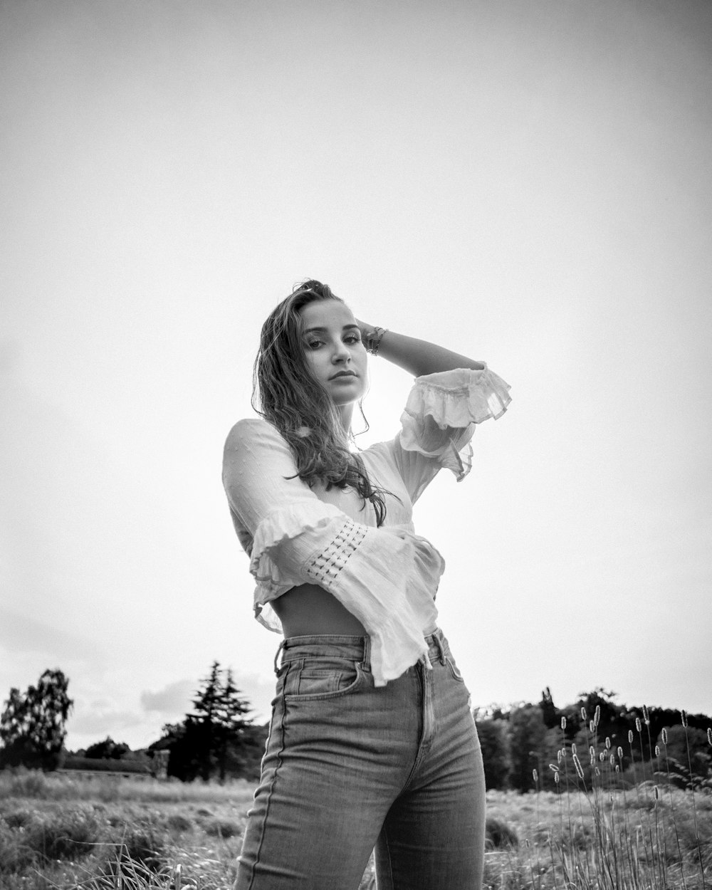 grayscale photo of woman in white long sleeve shirt and gray denim jeans