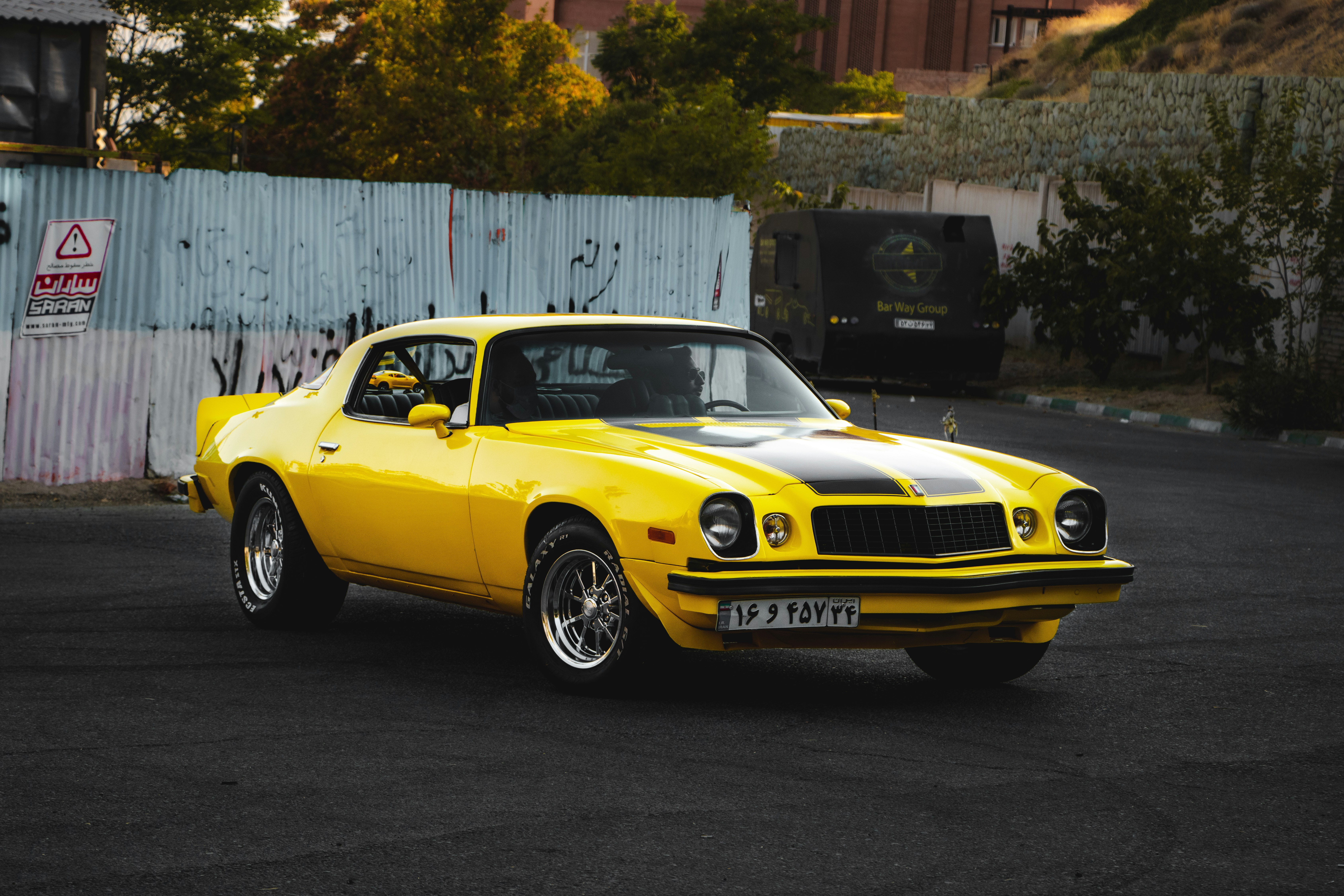 yellow chevrolet camaro parked beside white wall