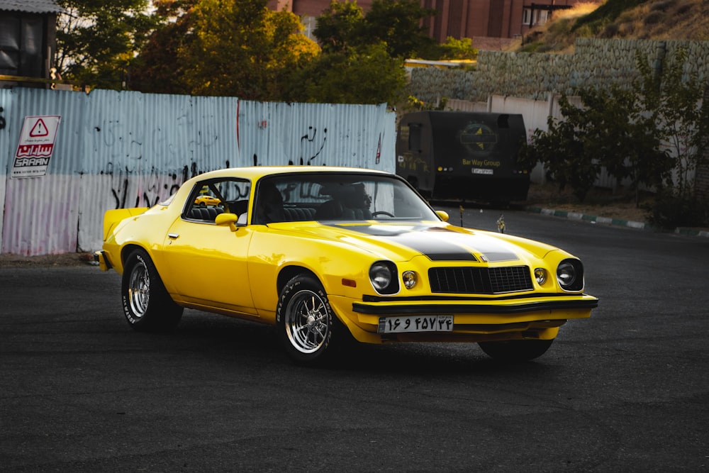 yellow chevrolet camaro parked beside white wall