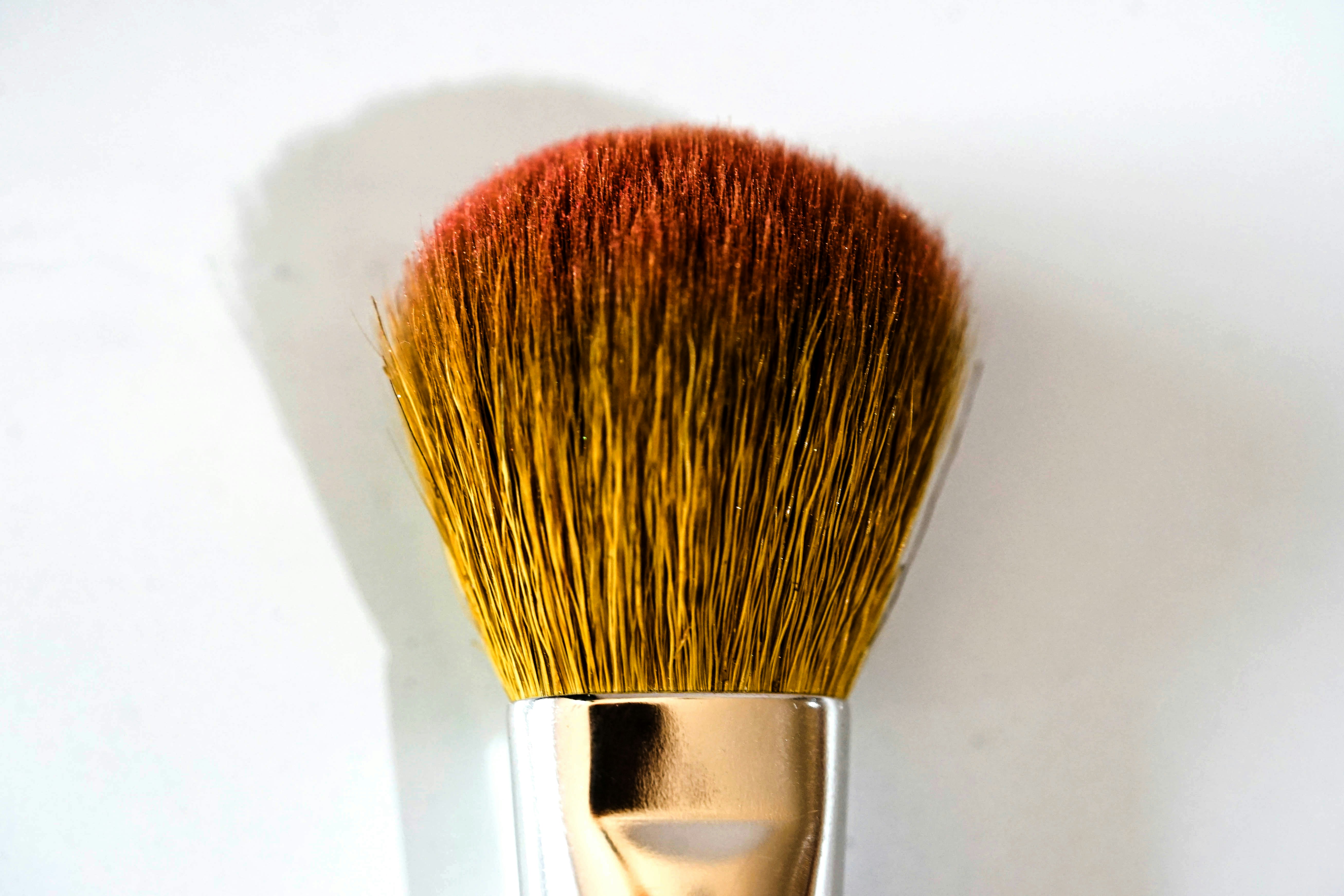 Makeup brush with blush on a white background.