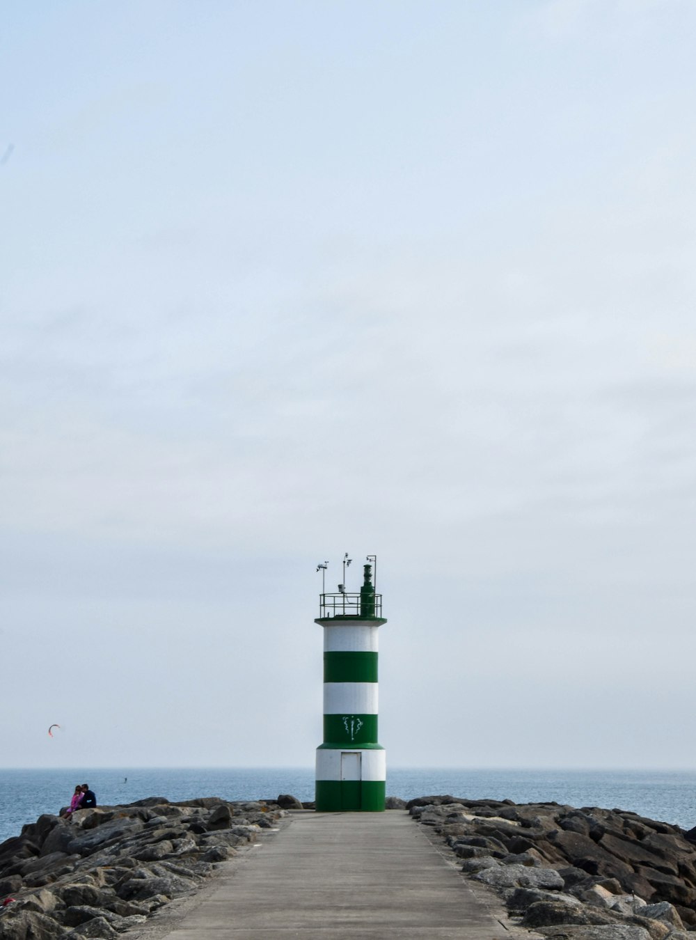 people on beach near lighthouse during daytime