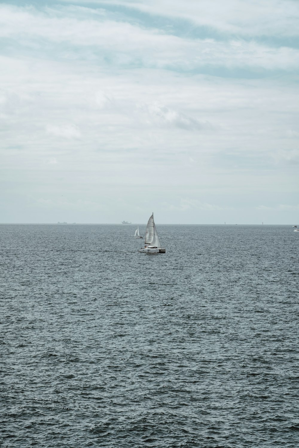 white sailboat on sea under white clouds during daytime