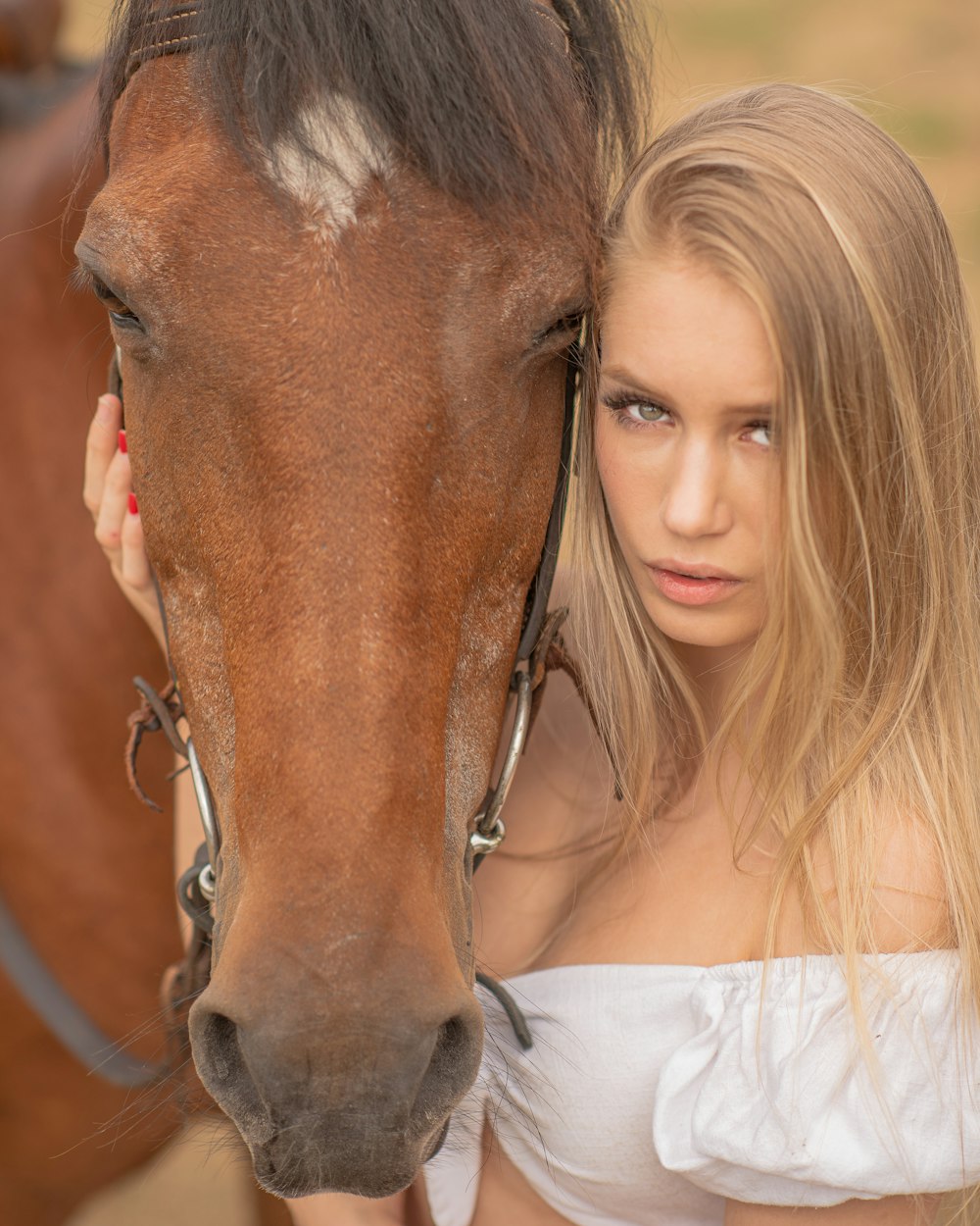 woman in white off shoulder shirt beside brown horse