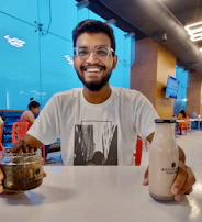A smiling customer holding a bottle of Pasaydan Amrut Juice in a sunlit kitchen.