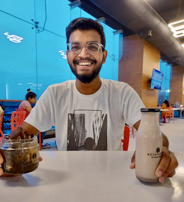 A smiling customer holding a jar of Dharmansh A2 Bilona Ghee in a cozy kitchen