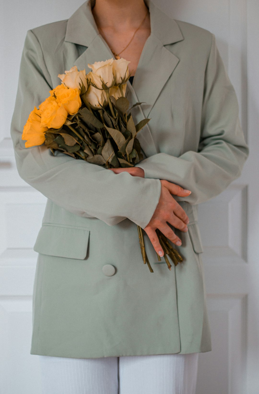 woman in gray coat holding yellow flower bouquet